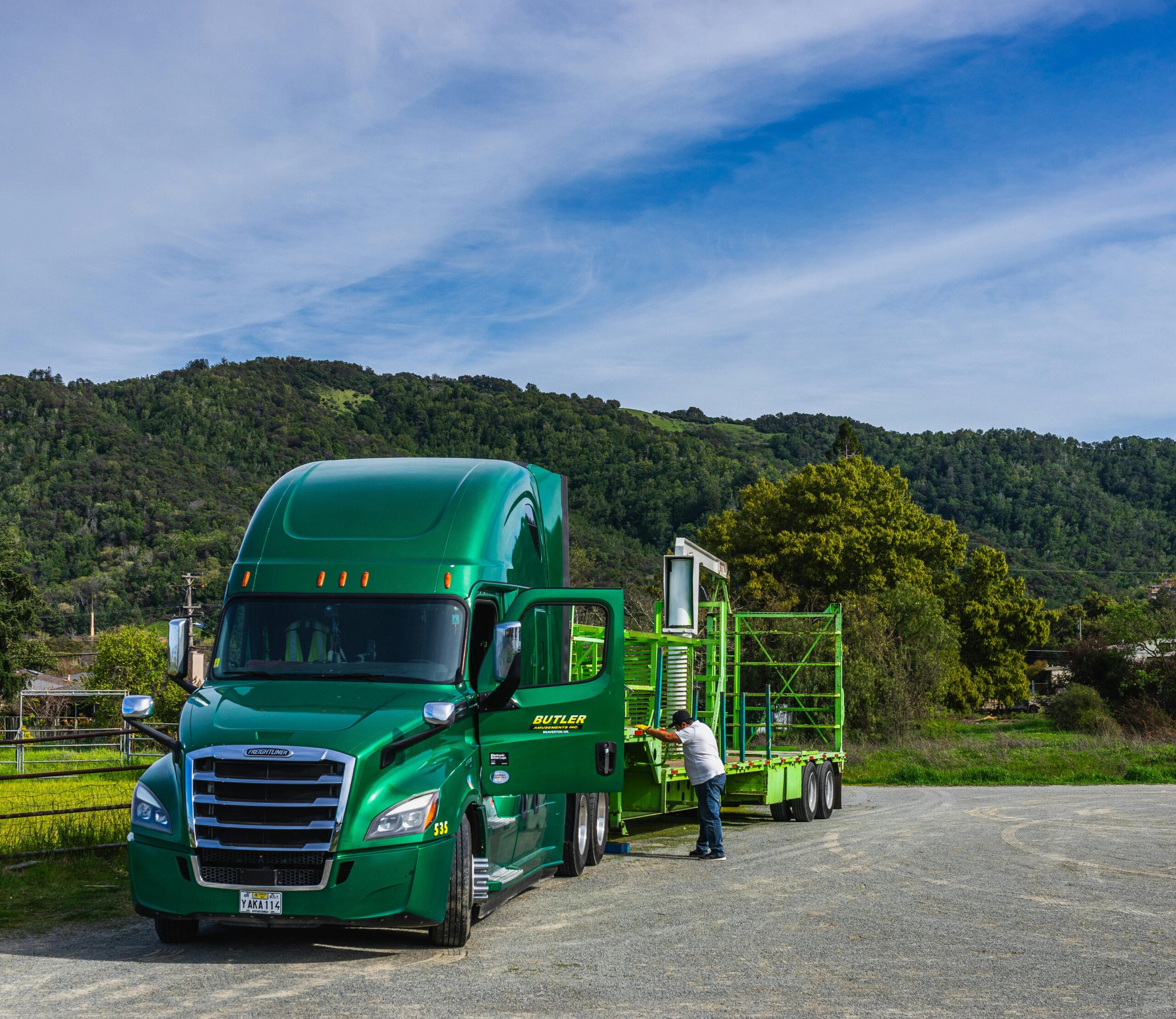 a green truck with its door opened and the driver on the side